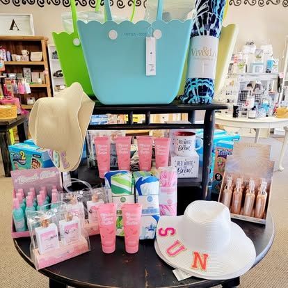 Beach supplies display: bags, sunscreen, hats, towels, and lotions on a round table.