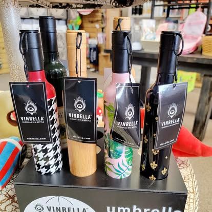 Umbrellas shaped like wine bottles on display, various patterns and colors, with tags that say 