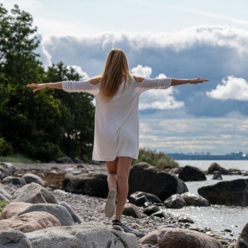 Woman standing on the shore with her arms open, feeling like herself again