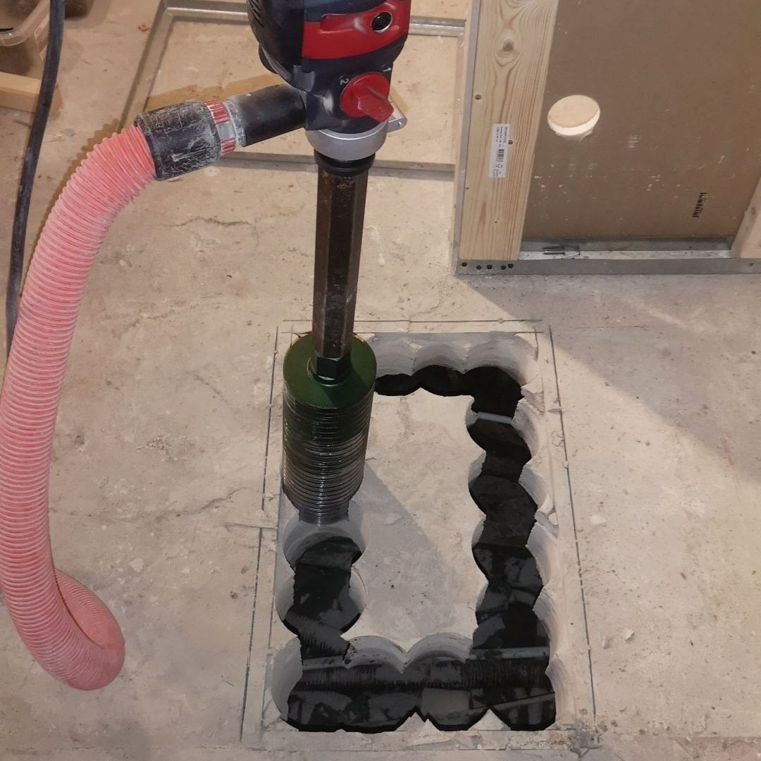 A drill is being used to cut a hole in the floor