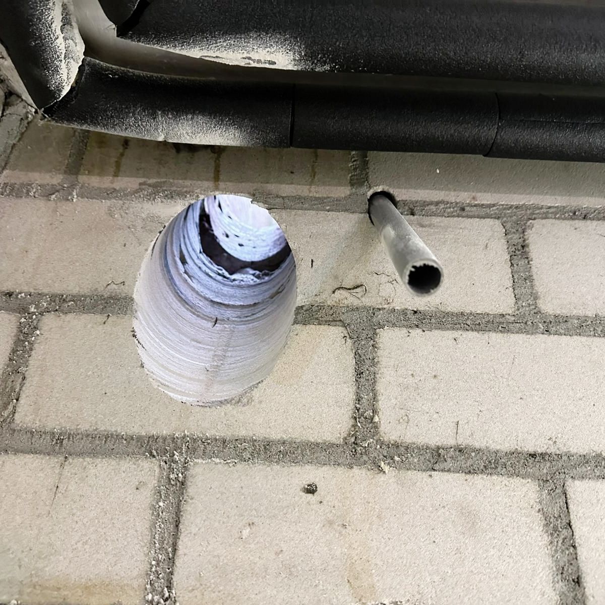 A hole in a brick wall with a pipe sticking out of it