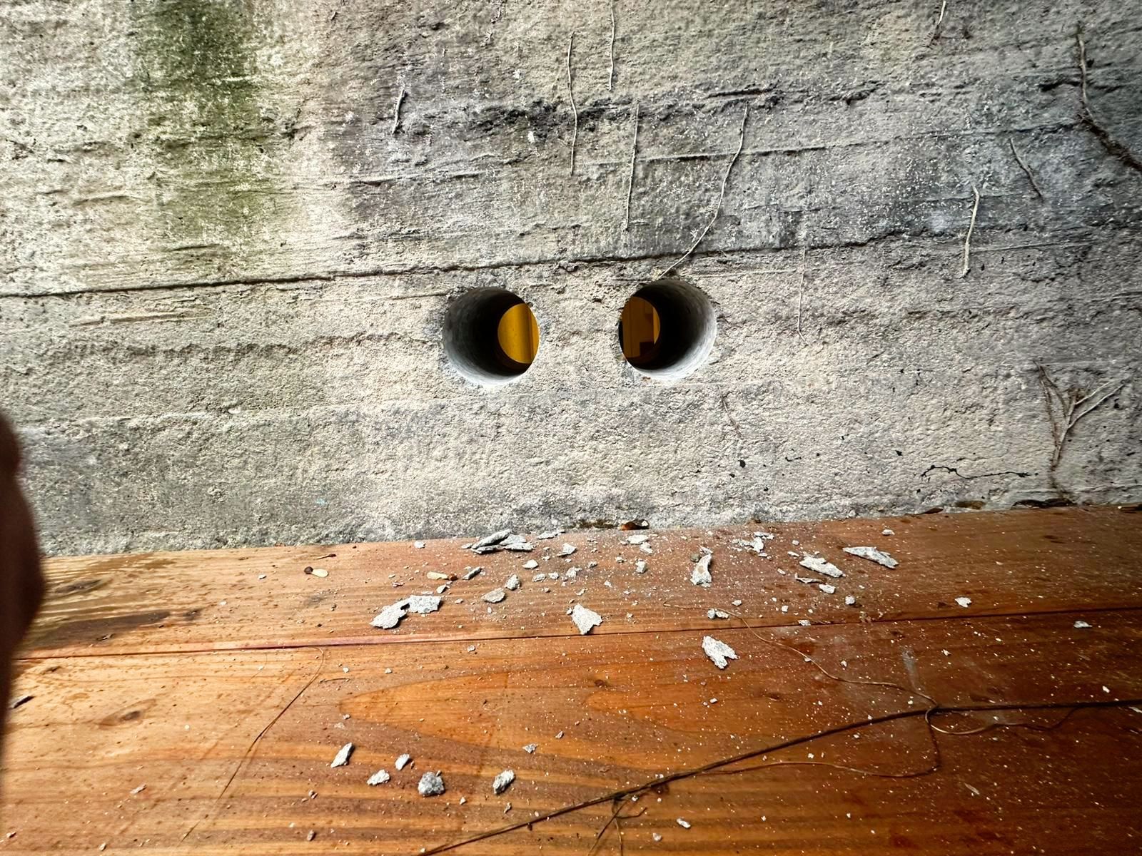 Een persoon staat voor een betonnen muur met twee gaten erin geboord