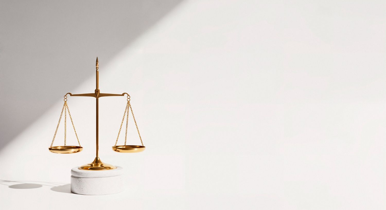 Gold balance scale on white background with a soft shadow