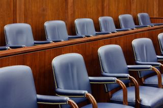 Empty blue chairs in a wood-paneled courtroom or conference room row