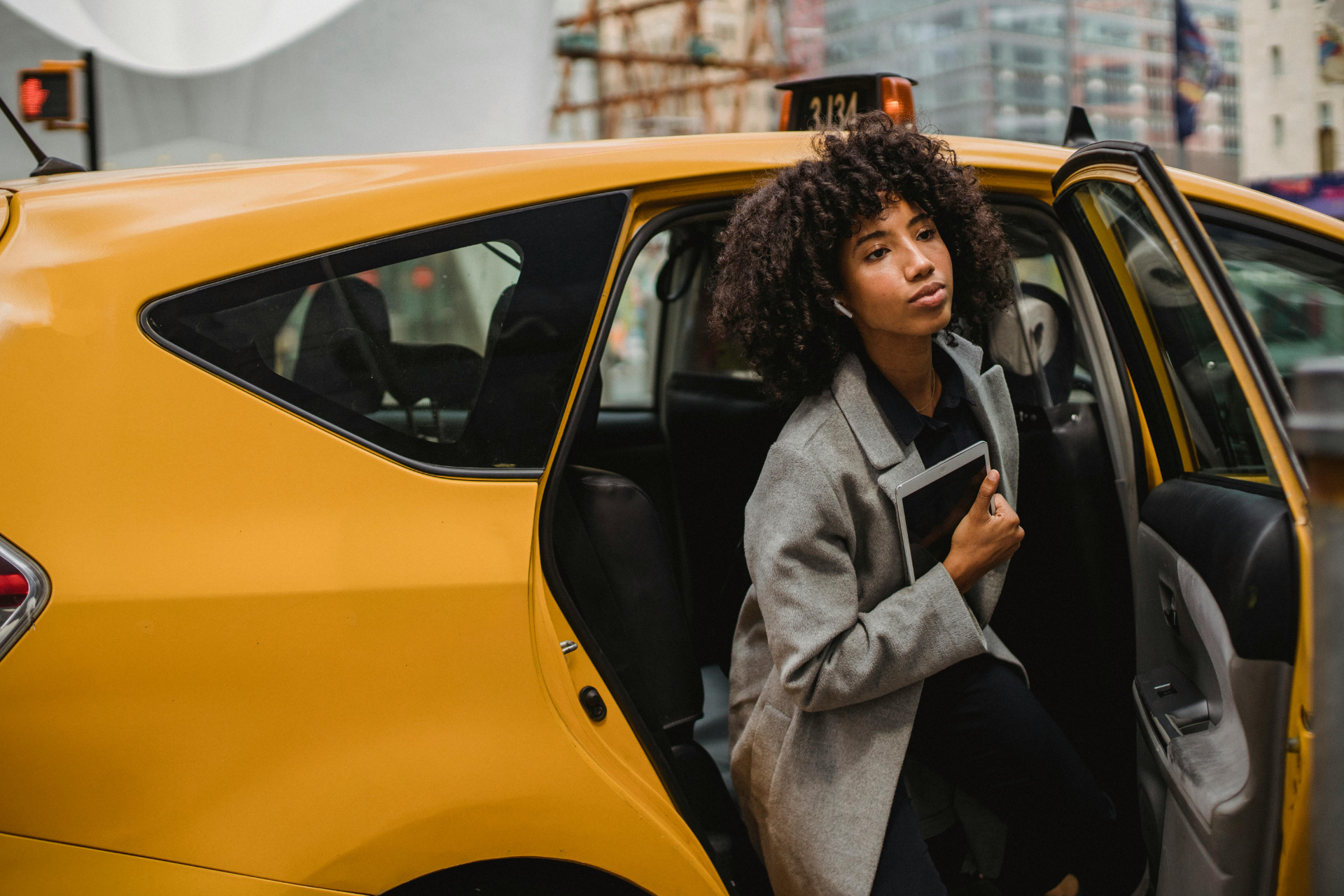 Woman standing in an open yellow taxi door on a city street