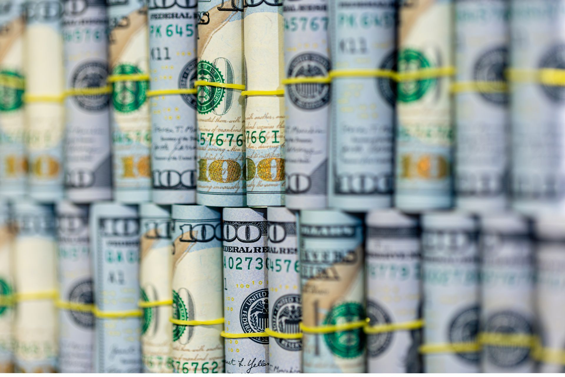 A bunch of rolls of money are tied together with rubber bands.
