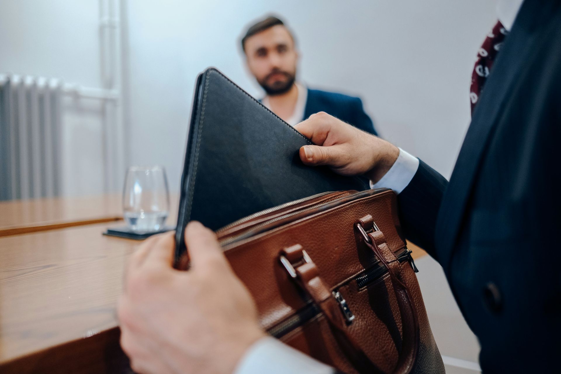 A man in a suit is holding a briefcase and a laptop.