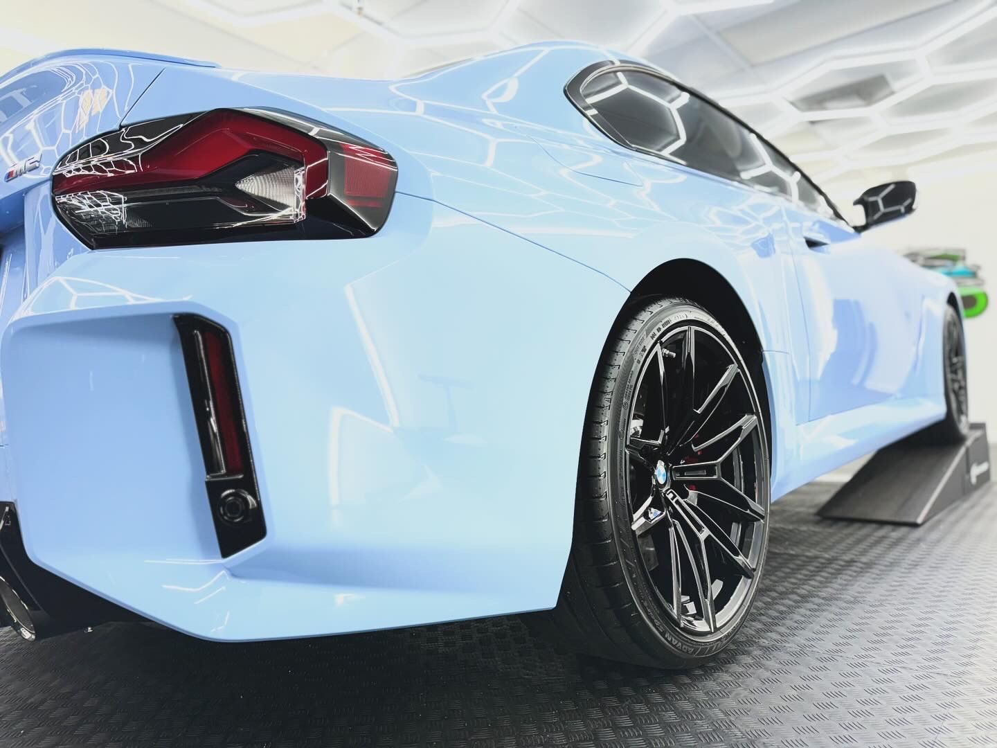 A blue sports car with black wheels is parked in a garage.
