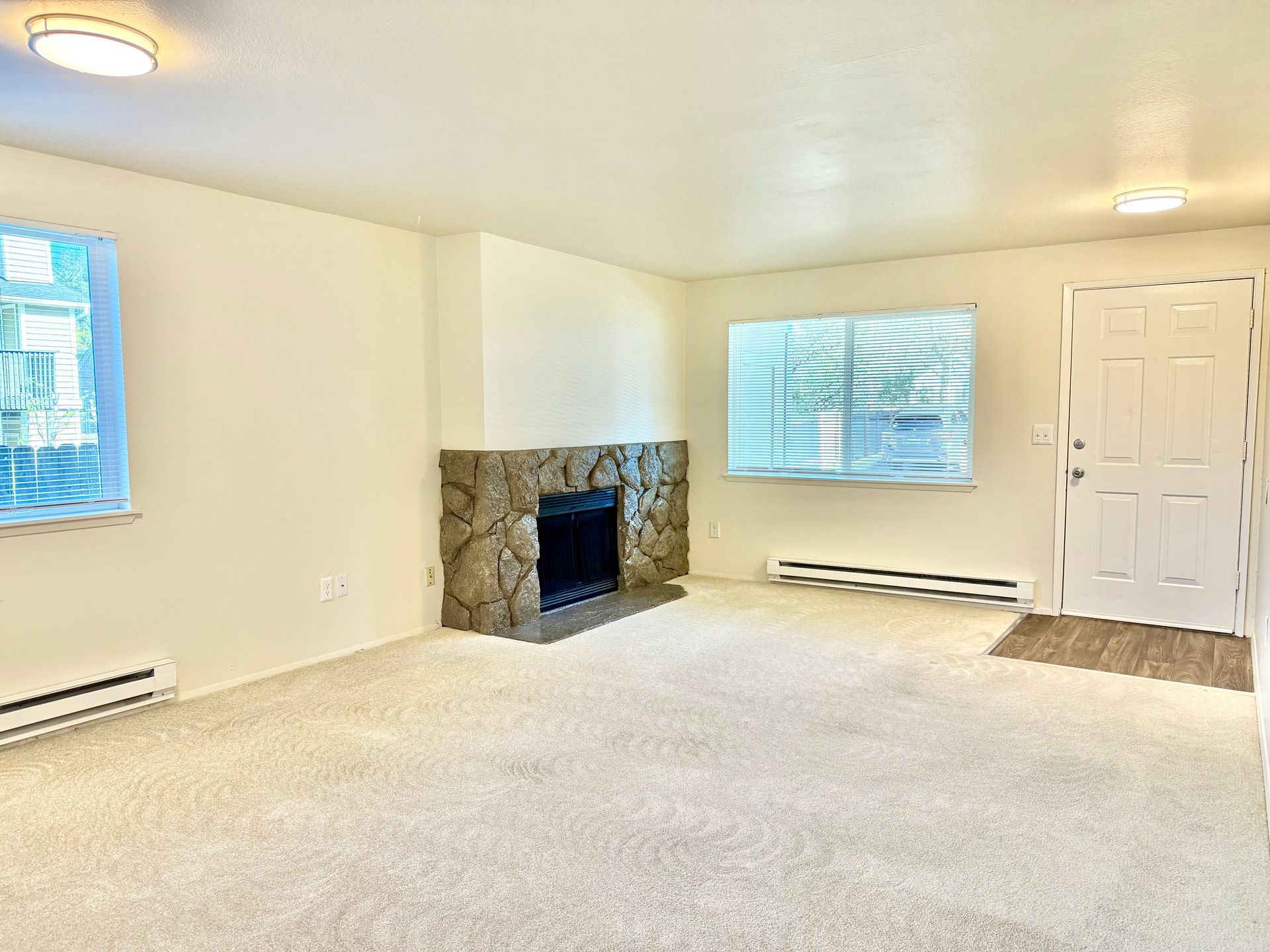 An empty living room with a fireplace and a window.