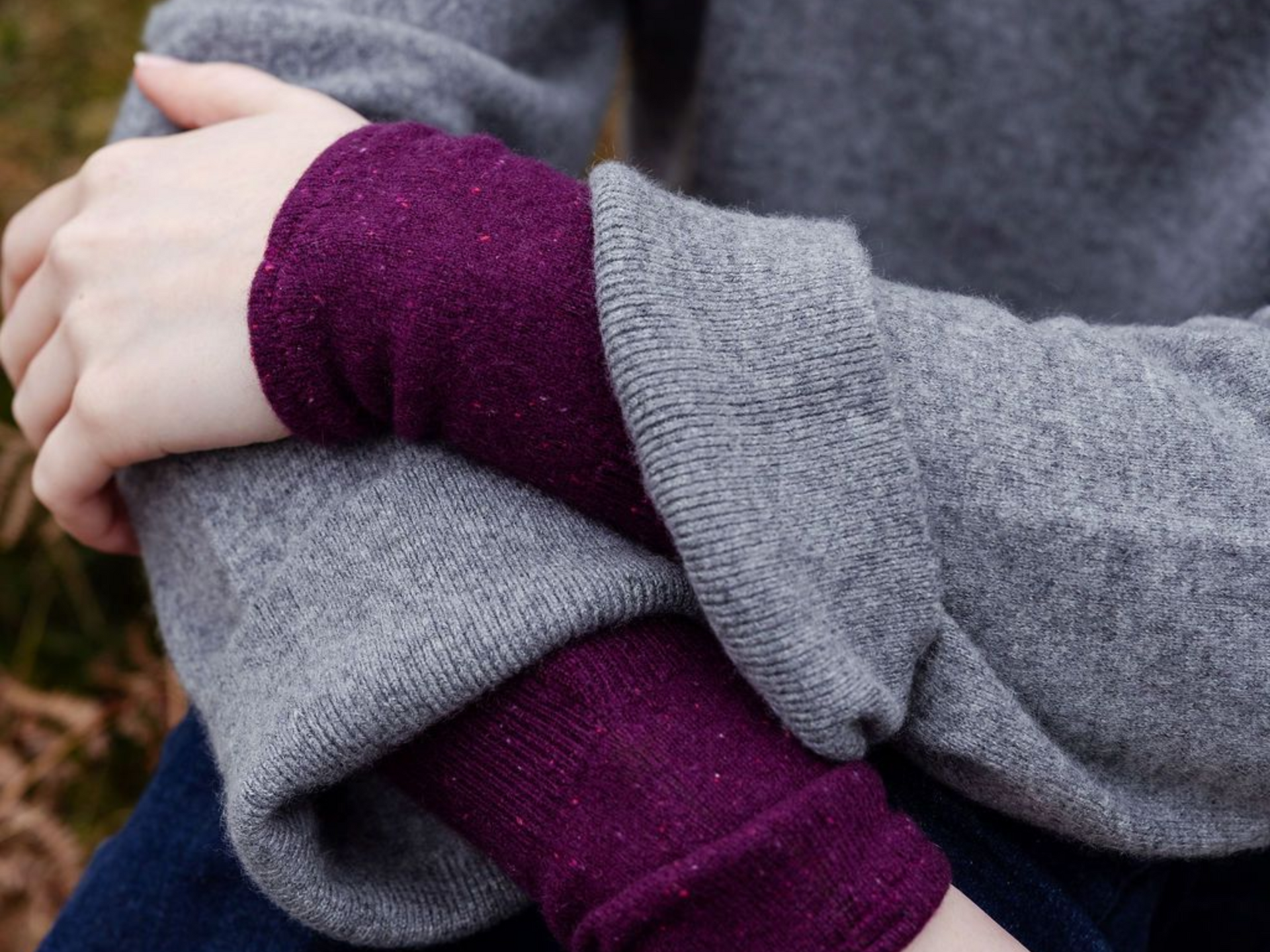photo of a womans arms wearing a cashmere jumper and a pair of burgundy cashmere wrist warmers