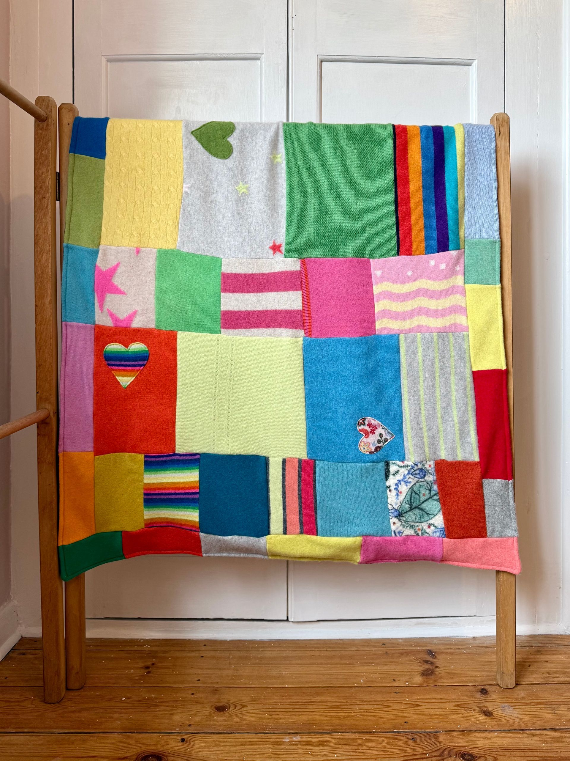 photo of a colourful cashmere patchwork blanket hanging over a vintage wooden clothes horse 