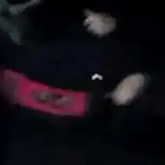 Een close-up van een persoon die een zwart shirt en een rode riem draagt.