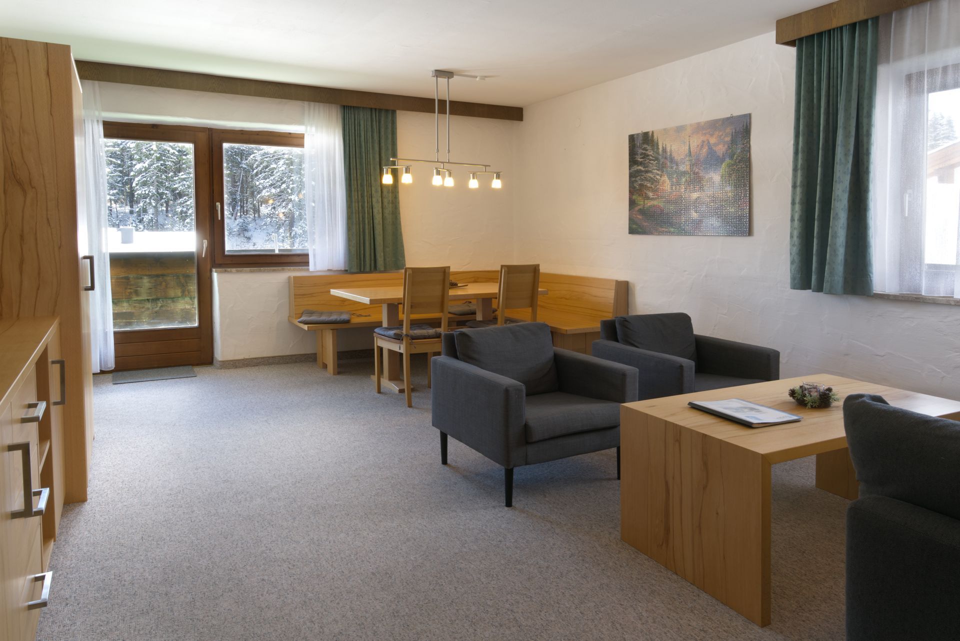 Een woonkamer met een tafel, stoelen en een schilderij aan de muur.