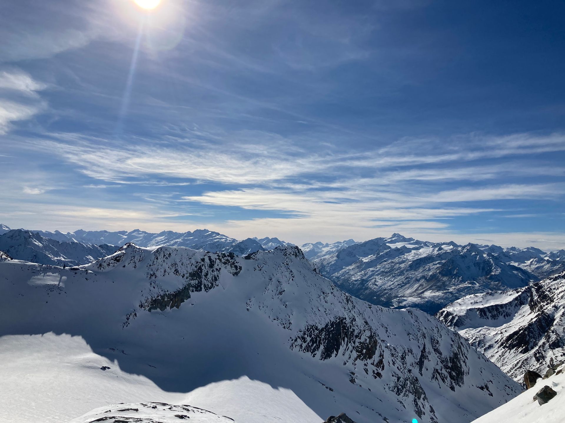 Skifahrerin auf einer verschneiten Tiroler Piste mit Blick auf Berggipfel bei klarem Herbstwetter in den Alpen