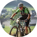 Een man rijdt op een mountainbike op een met gras begroeide heuvel.