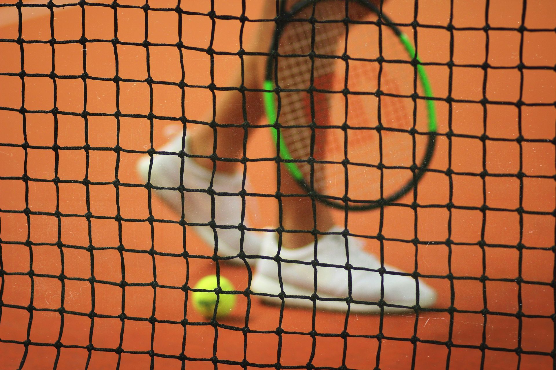 Ein Tennisspieler schlägt mit einem Schläger einen Tennisball.
