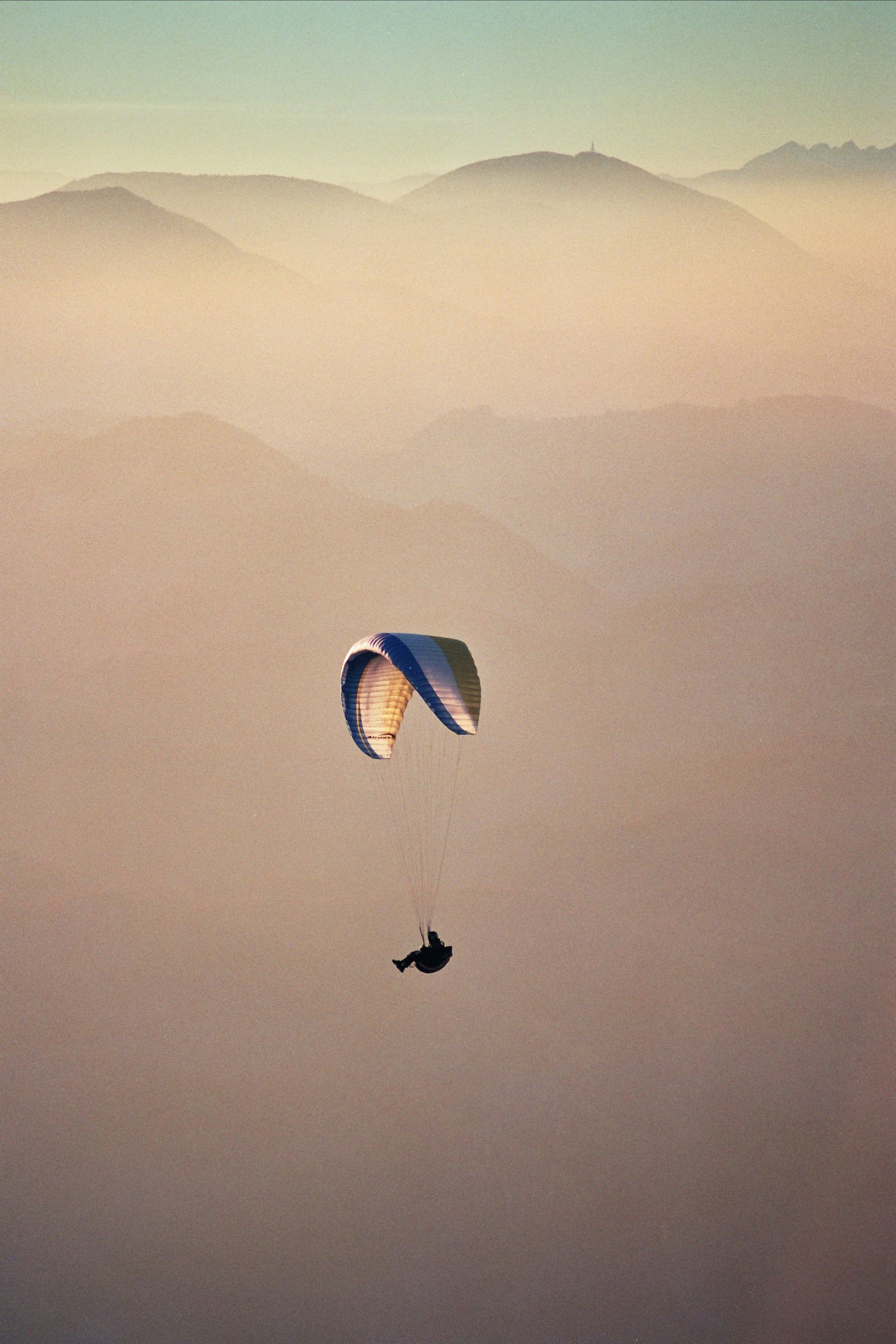 Eine Person fliegt mit einem Fallschirm über eine Bergkette.