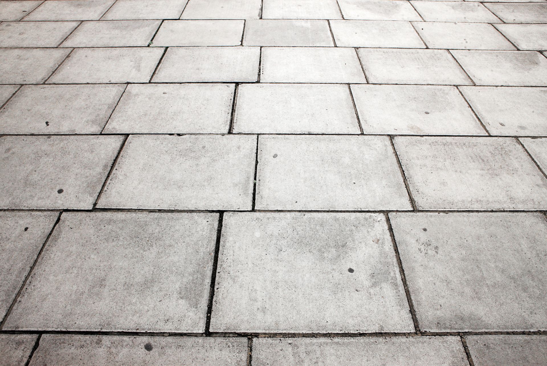 Gray paving stones on a ground, arranged in a grid pattern, perspective view.