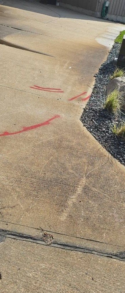 Outdoor concrete path with red spray markings and a low stone border beside a building