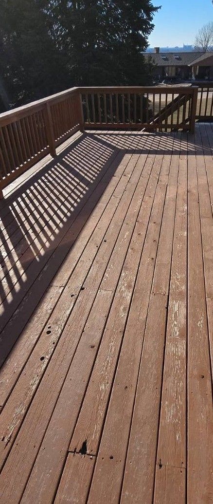 Wooden deck with railings casting striped shadows in bright sunlight