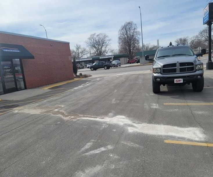 Parking lot beside a brick building, with a parked silver pickup truck in the foreground.