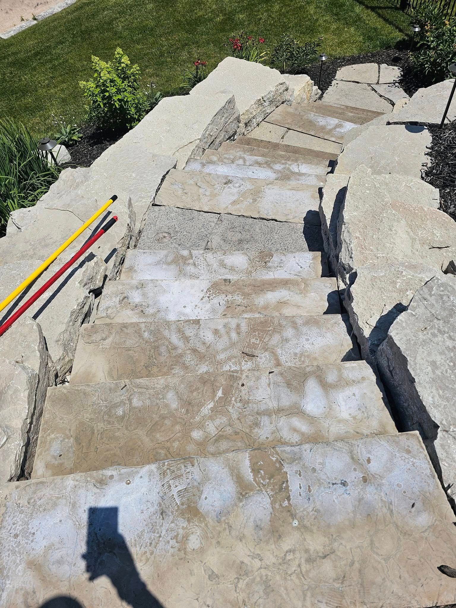 Broken concrete steps with a deep crack, viewed outdoors beside grass and two colored cables.