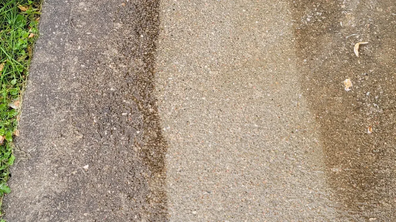 Close-up of a weathered concrete path with a dark strip on the left and grass along the edge