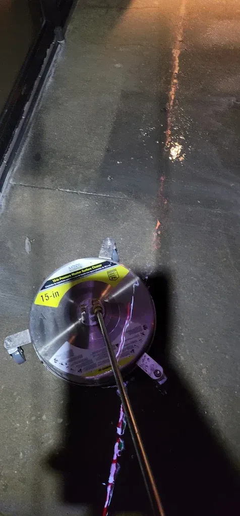 Purple tape measure on a dark sidewalk at night, with a crack line and a curb visible.