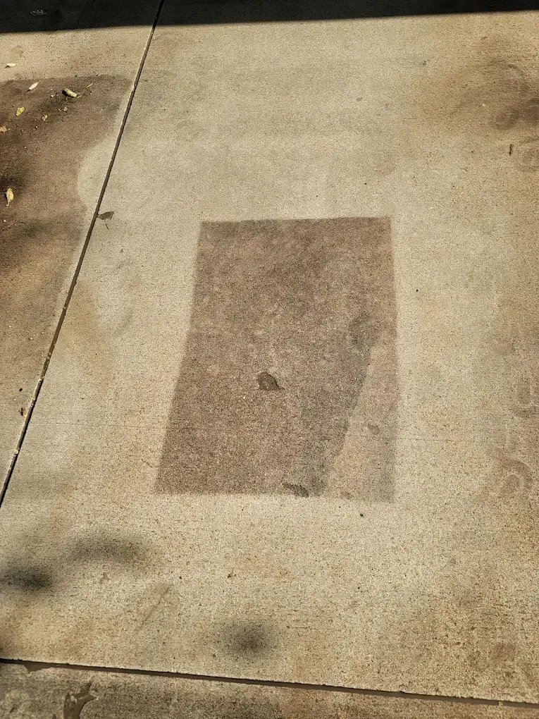 Concrete sidewalk with a dark rectangular patch in the center.