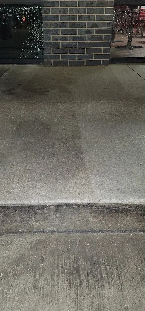 Concrete sidewalk with a curb and brick building wall at the top edge