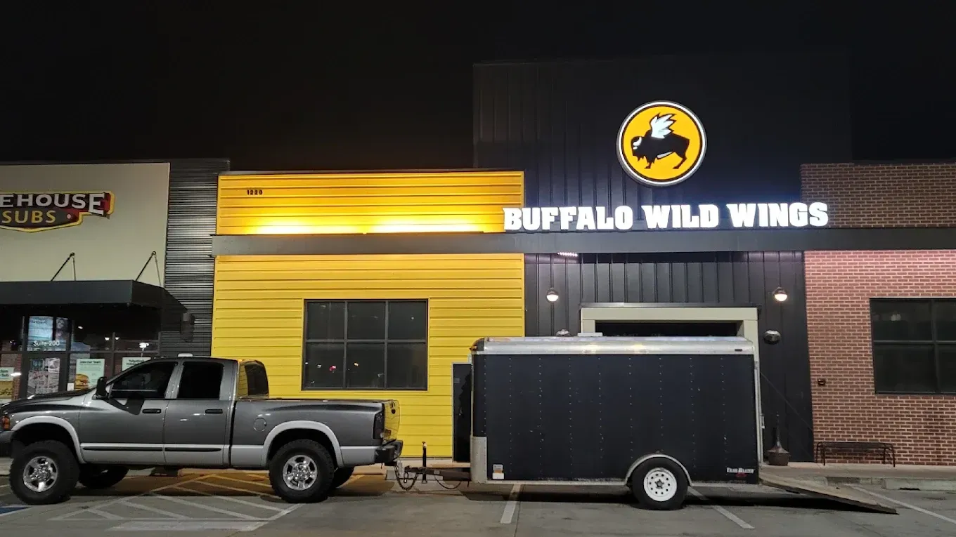 Buffalo Wild Wings storefront at night with a parked pickup truck and trailer in front