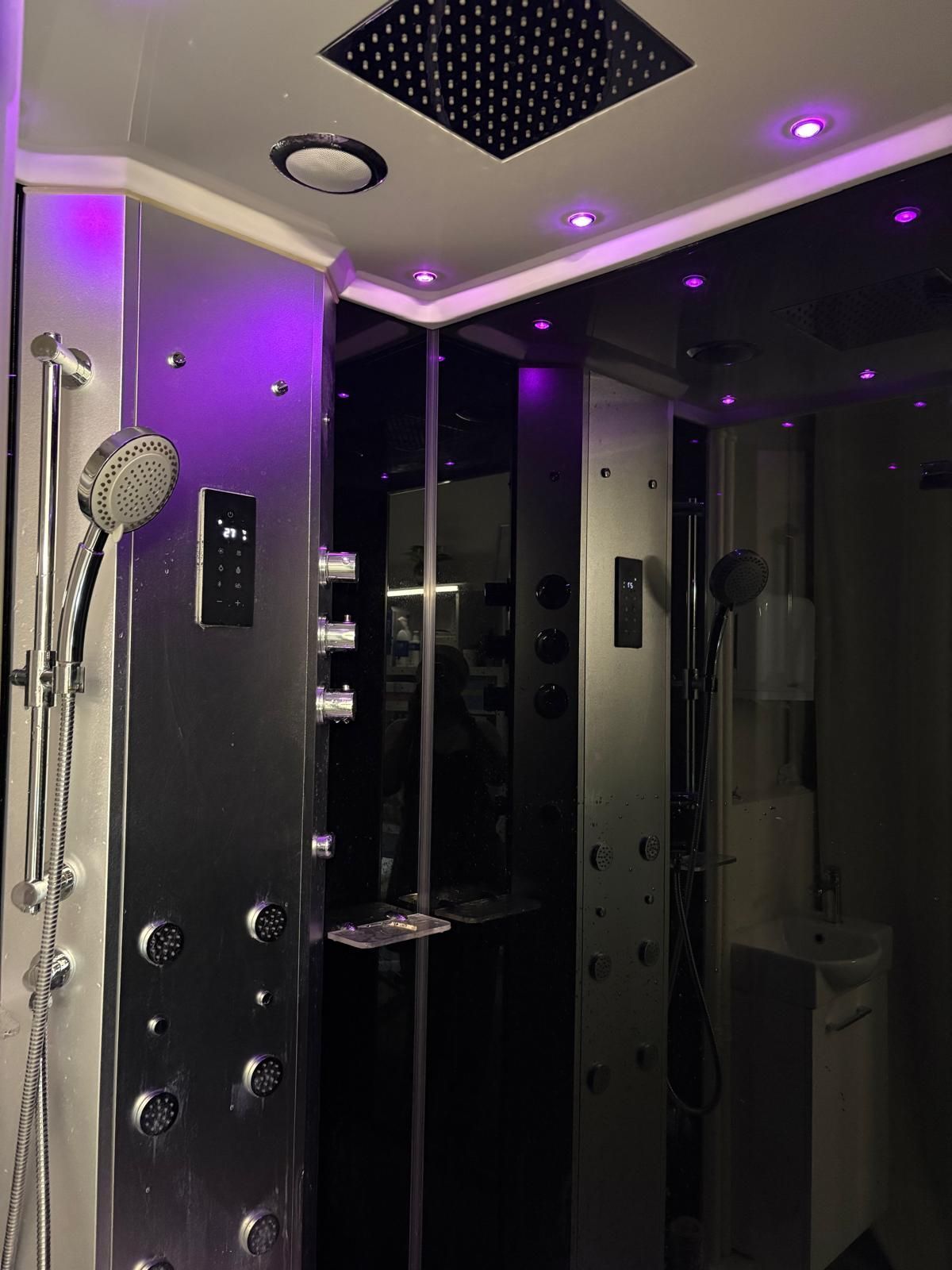 Douche moderne avec panneaux noirs, commandes chromées et éclairage LED violet dans une salle de bain élégante