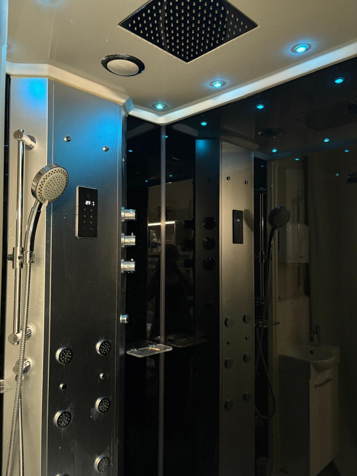 Cabine de douche moderne avec robinetterie chromée, éclairage d'ambiance bleu et portes en verre
