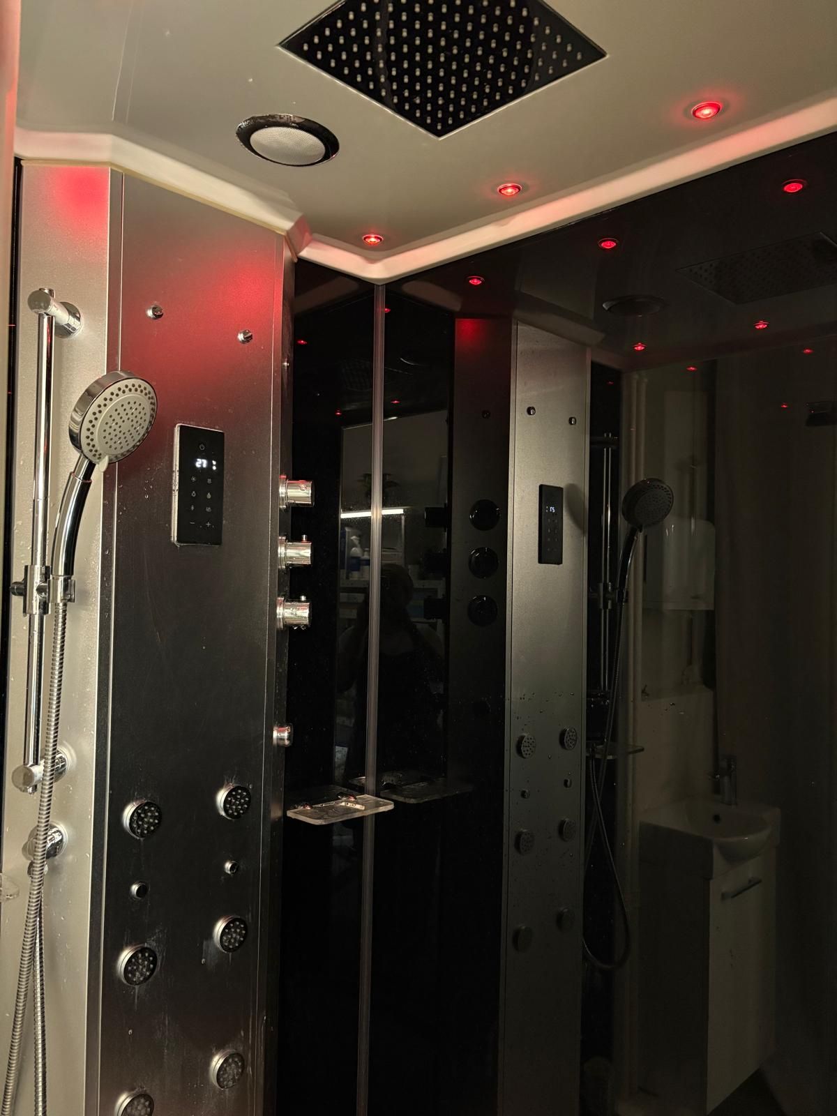 Cabine de douche moderne avec portes en verre, robinetterie chromée et éclairage d'ambiance LED rouge
