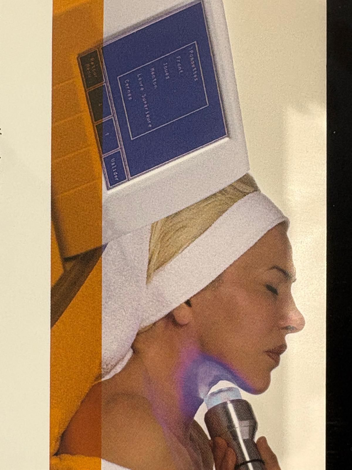 Une femme parle dans un microphone, portant un foulard blanc et un chapeau bleu en forme de livre.