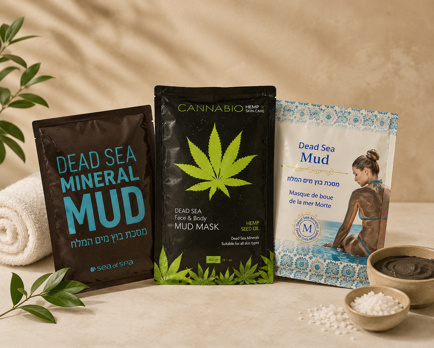 Trois sachets de produits de soin et un bol de sels de bain blancs sur un fond beige évoquant un spa.