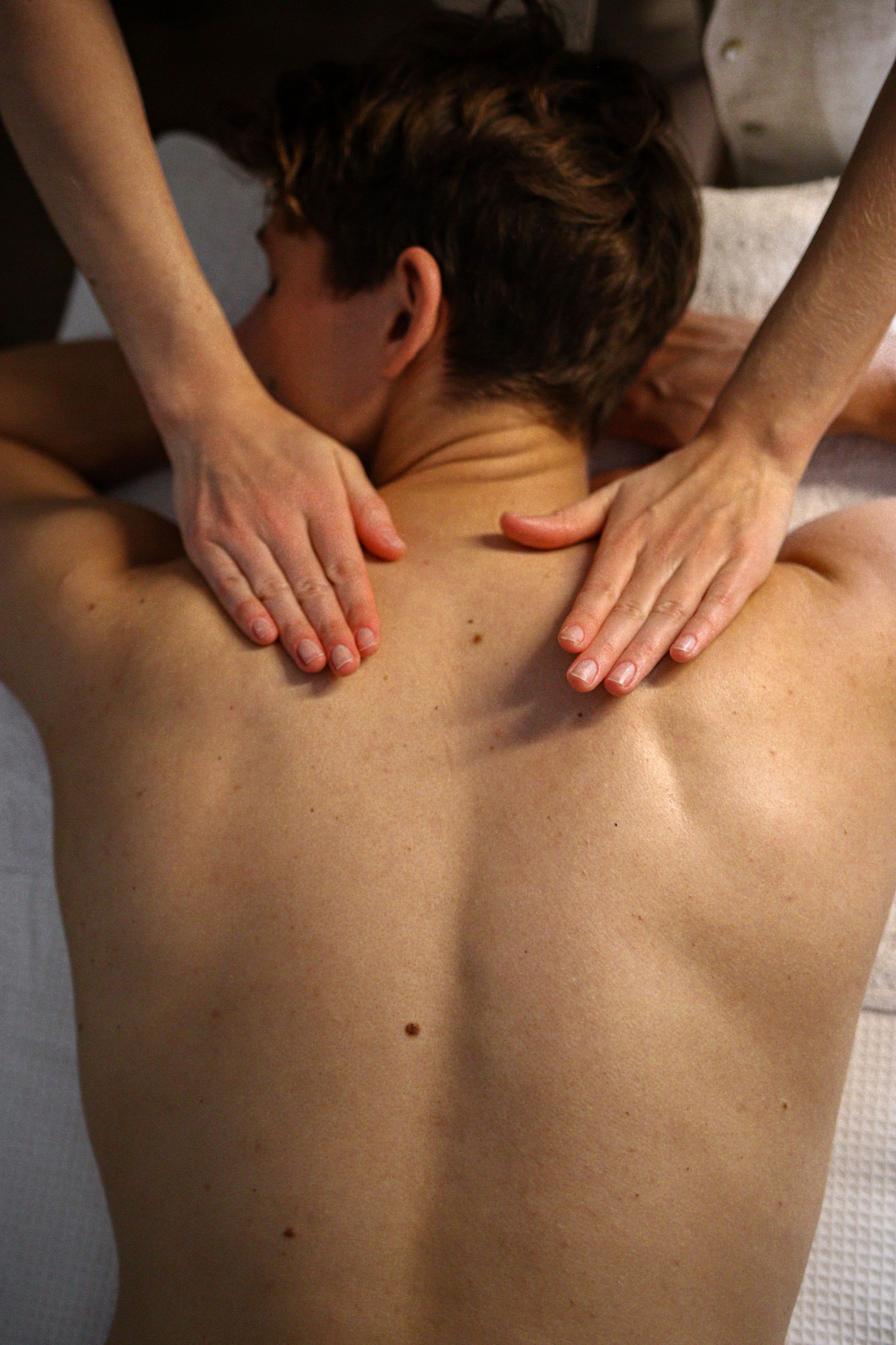 Les mains appuient sur le haut du dos et les épaules d'une personne pendant un massage.