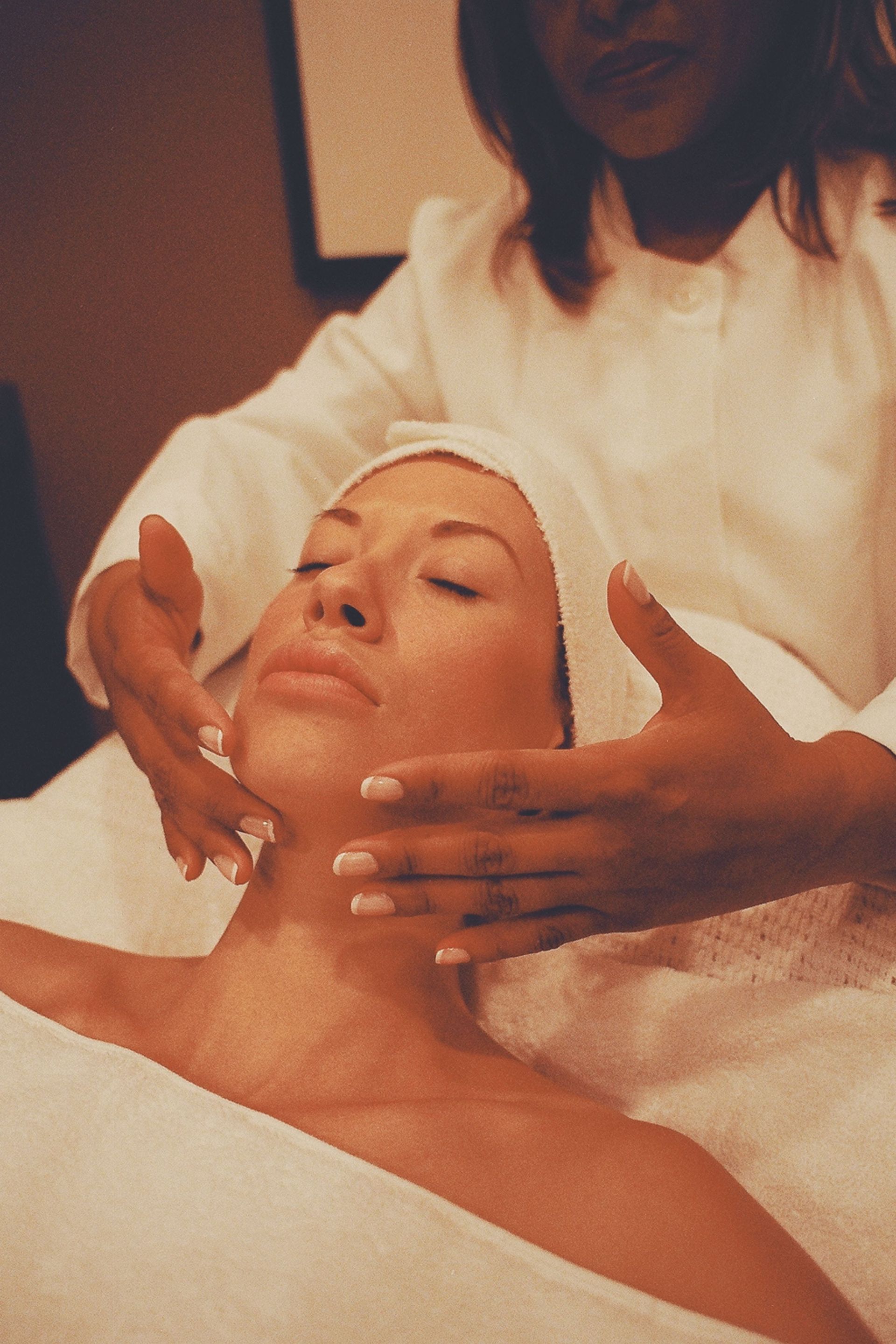 Massage facial de spa avec le client allongé et le praticien appliquant une lotion.