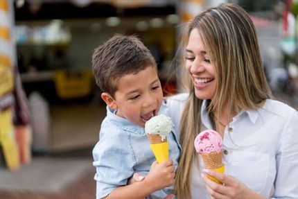 Woman and young boy smiling while holding ice cream cones in a shop