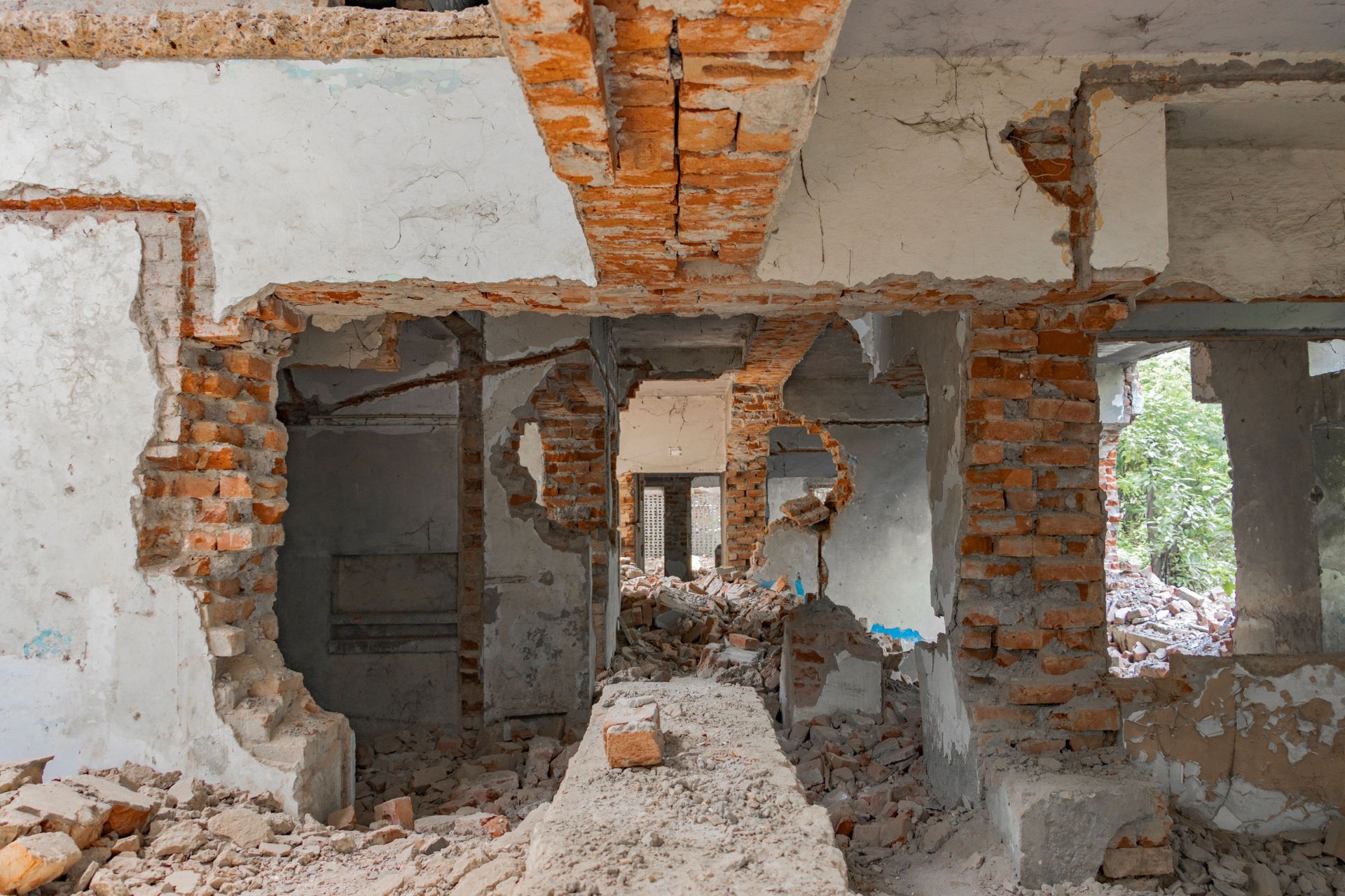 Dilapidated interior with exposed brick walls, broken plaster, and rubble on the floor.