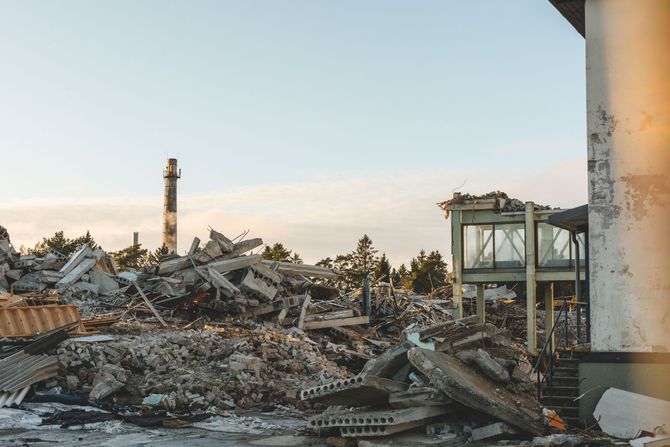 Collapsed building rubble with a damaged structure and chimney at sunset