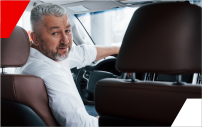 Um homem está sentado no banco do motorista de um carro.