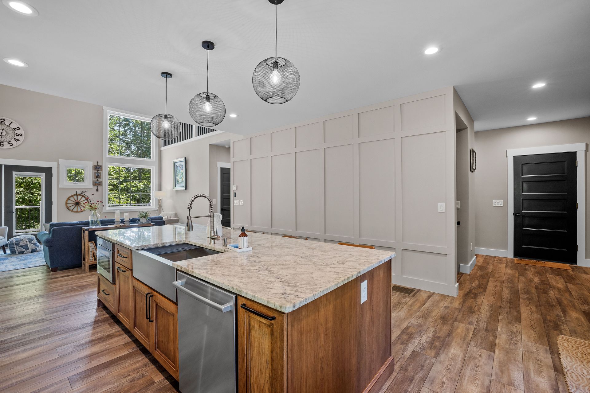 Cuisine moderne avec un grand îlot central, des appareils électroménagers en acier inoxydable et un parquet.