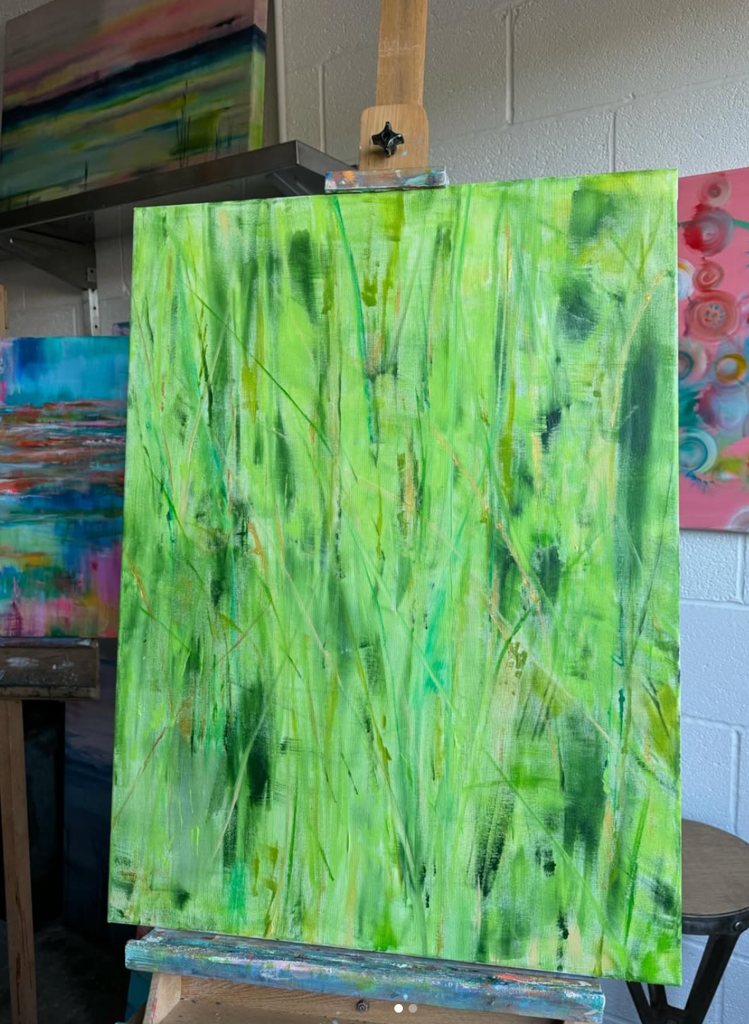 Abstract painting of tall green grass on an easel; studio setting.