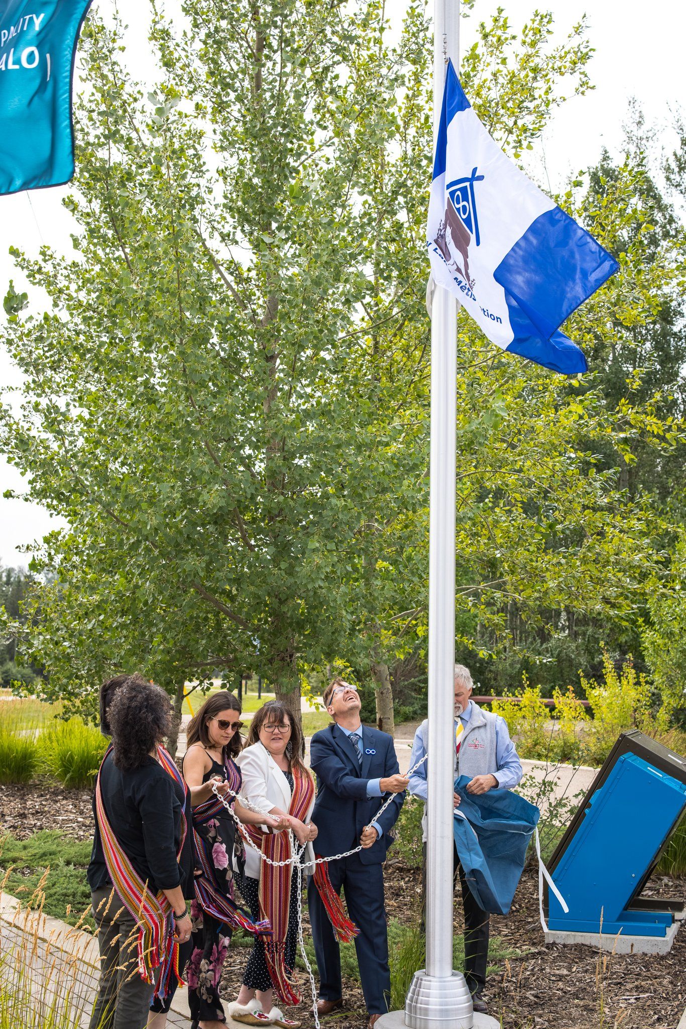 Group cuts ribbon raising flag in park.