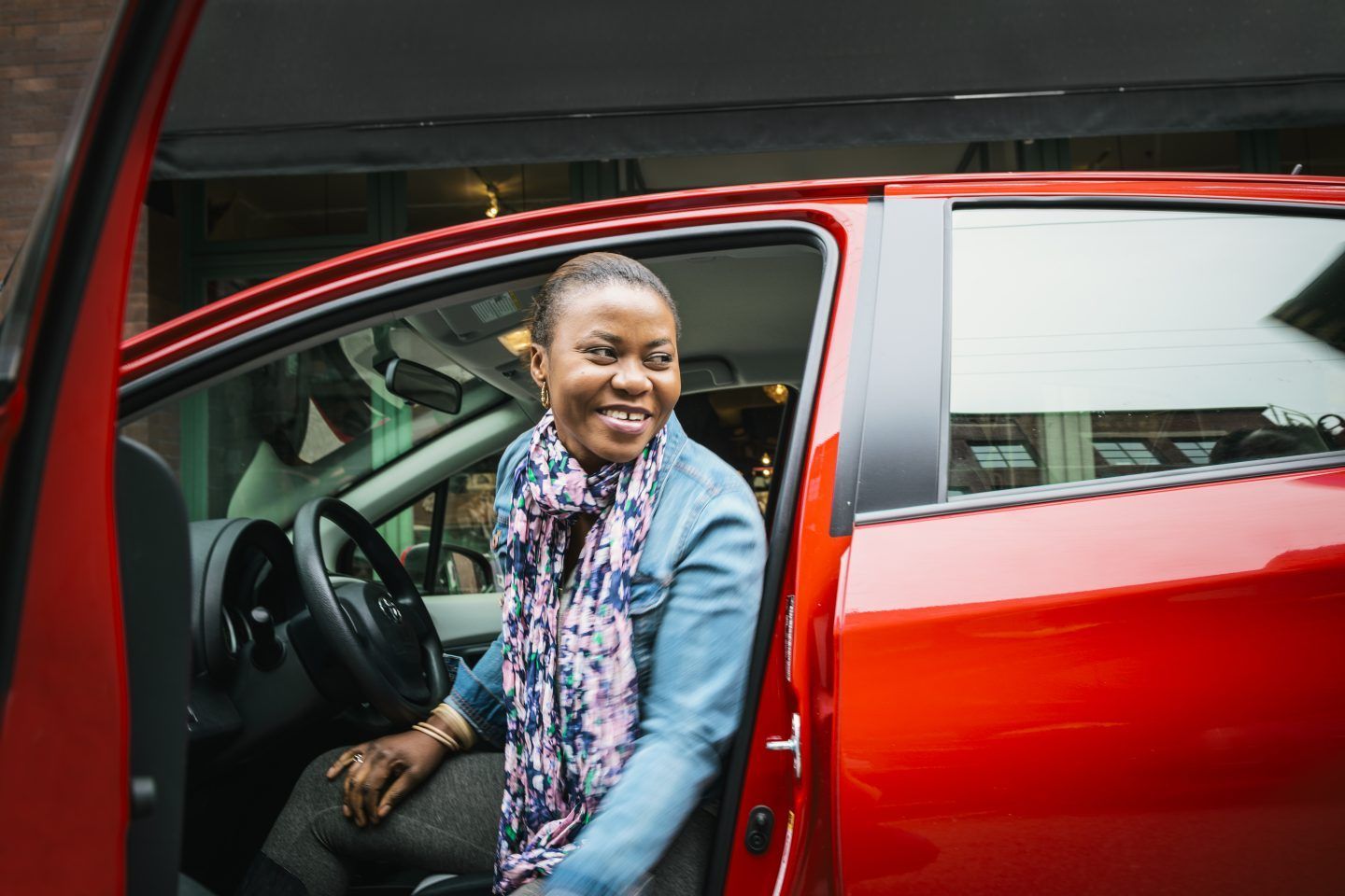 a young woman smiles while looking out her car door