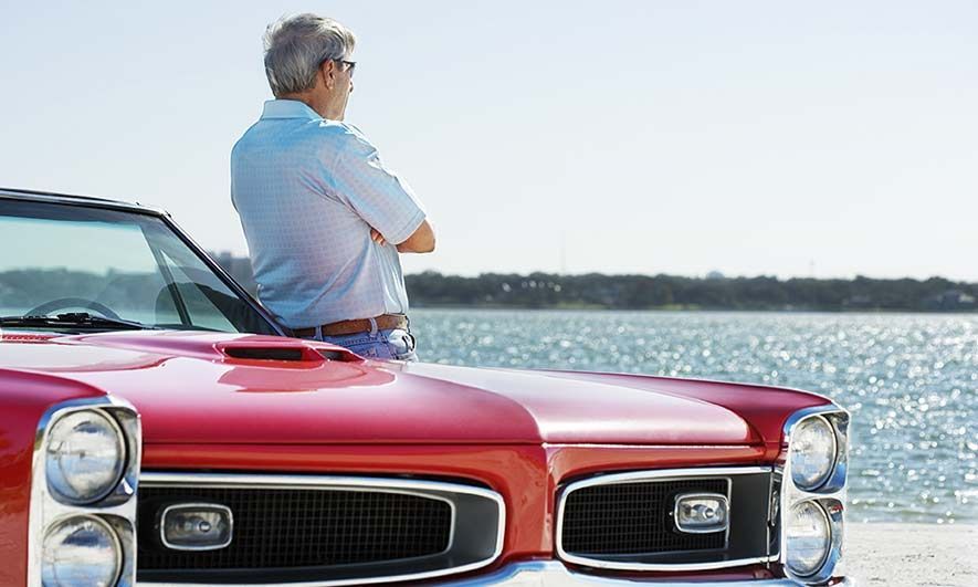man leans against his vintage car knowing he has antique auto insurance
