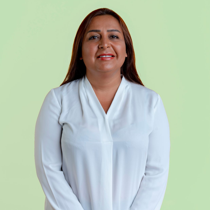 Woman in a white blouse smiling against a light green background