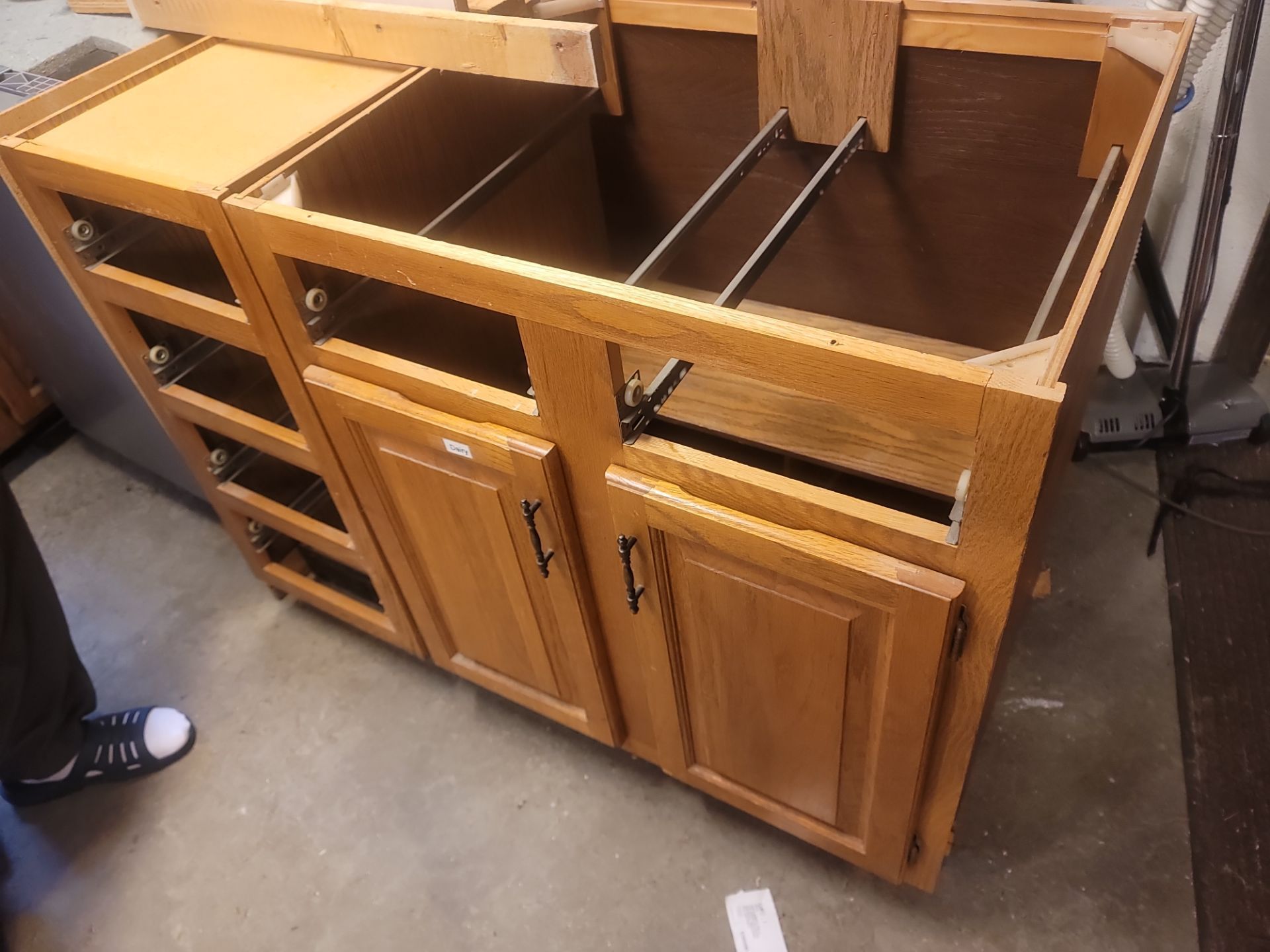 Wooden kitchen cabinet base with sink openings and drawers in a workshop