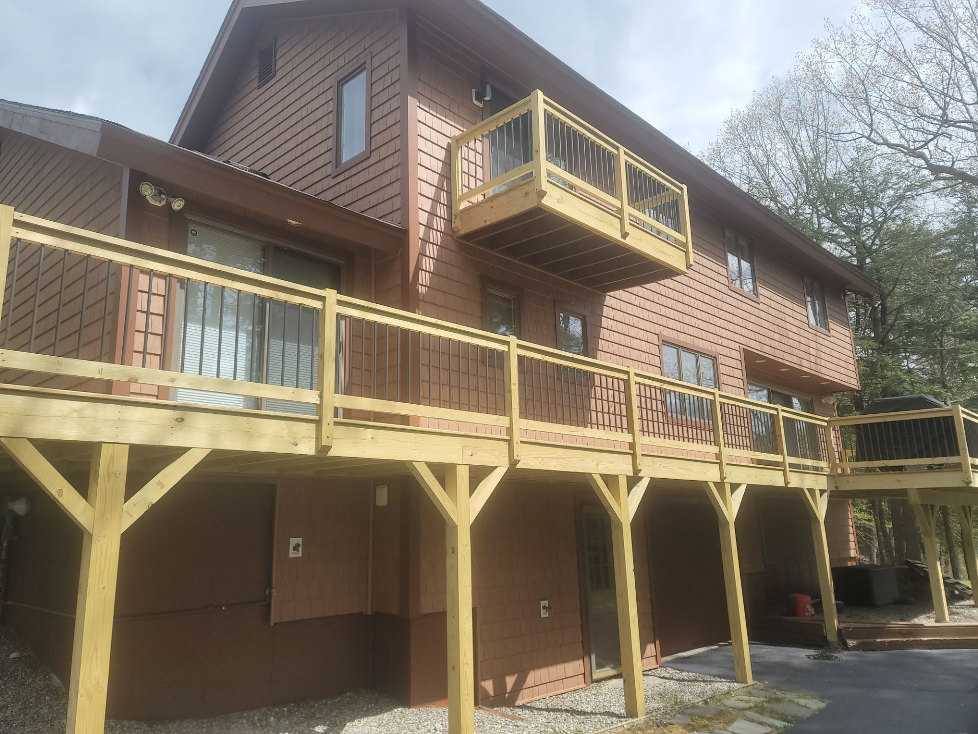 Brown apartment building with yellow wooden balconies and support posts on a sloped exterior.
